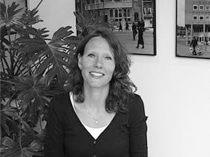 Portret van Inge Baggerman-Scherpenisse op kantoor, voor een plant en ingelijste stadsfoto's
